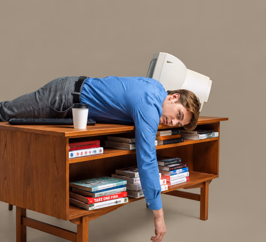 A man slumped face-down across a wooden desk full of books