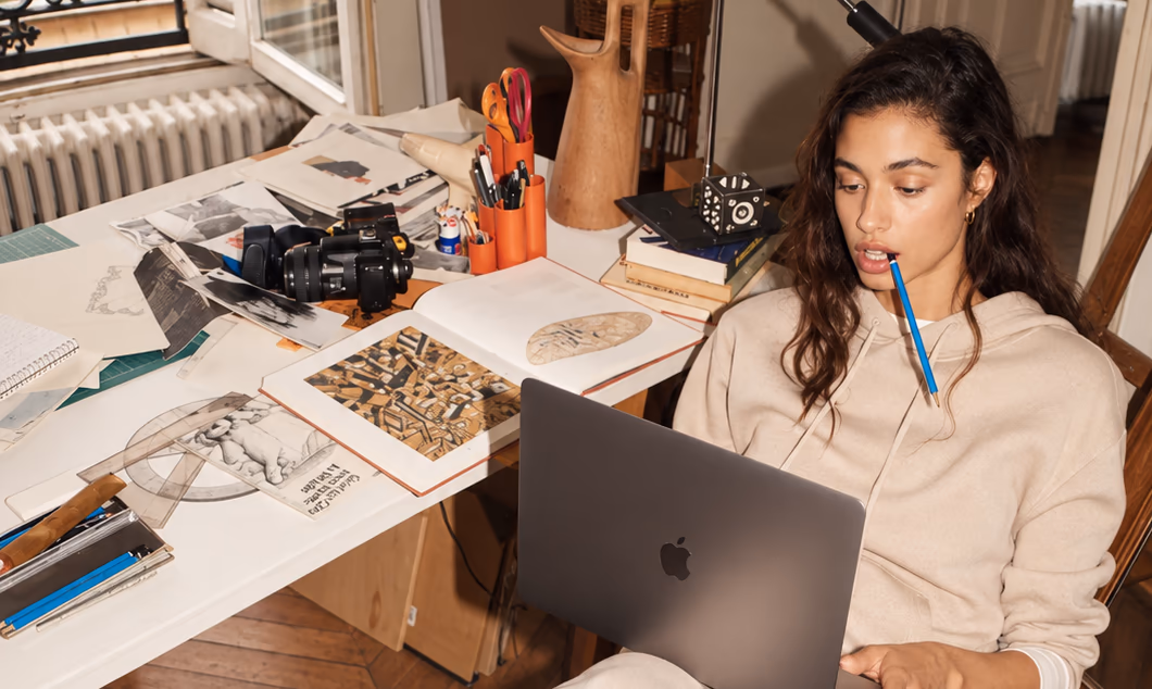 A woman working on a laptop on the floor of a busy studio